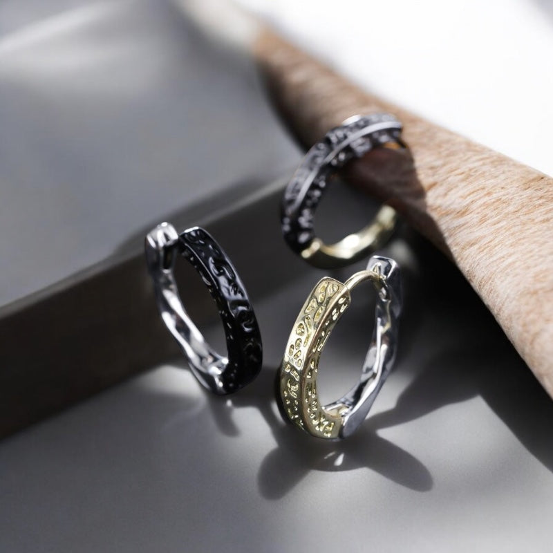 Paire de boucles d'oreilles anneaux pour homme, élégamment texturées, disponibles en versions bicolores noir et argent ou doré et argent. Motifs finement gravés pour un style chic et masculin 