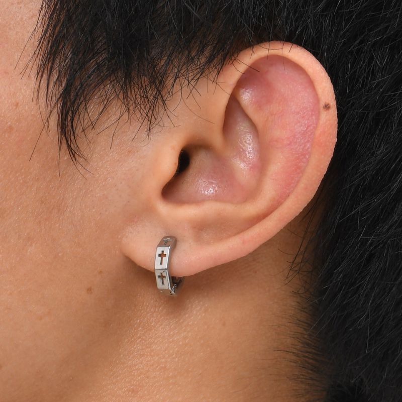 Créole homme en acier inoxydable finition argentée avec croix – portée à l’oreille.