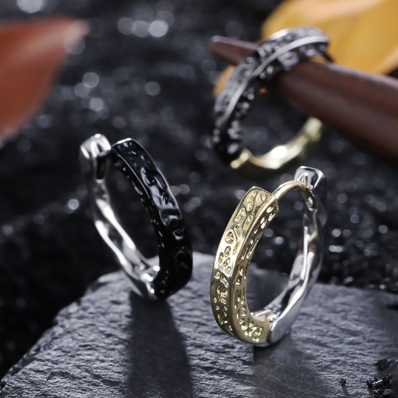 Paire de boucles d'oreilles anneaux pour homme, élégamment texturées, disponibles en versions bicolores noir et argent ou doré et argent. Motifs finement gravés pour un style chic et masculin