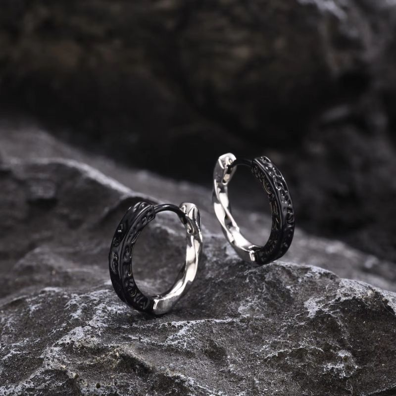  Boucle d'oreille créole pour homme en acier inoxydable et argent plaqué noir portée à l'oreille. Bijou élégant avec un contraste subtil entre la partie noire sculptée et la finition argentée brillante