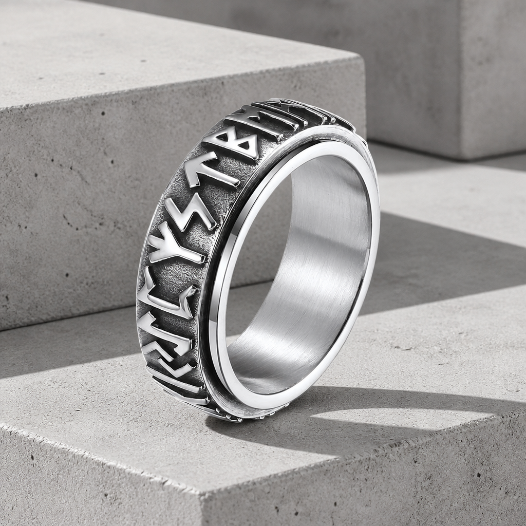 Bague viking anti-stress en acier argenté, anneau tournant gravé de runes, posée sur béton