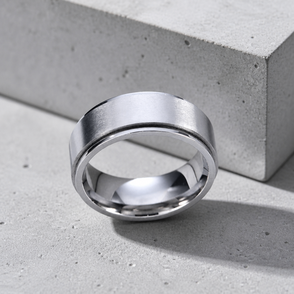Bague anti-stress argent homme en acier inoxydable brossé, anneau tournant, posée sur béton