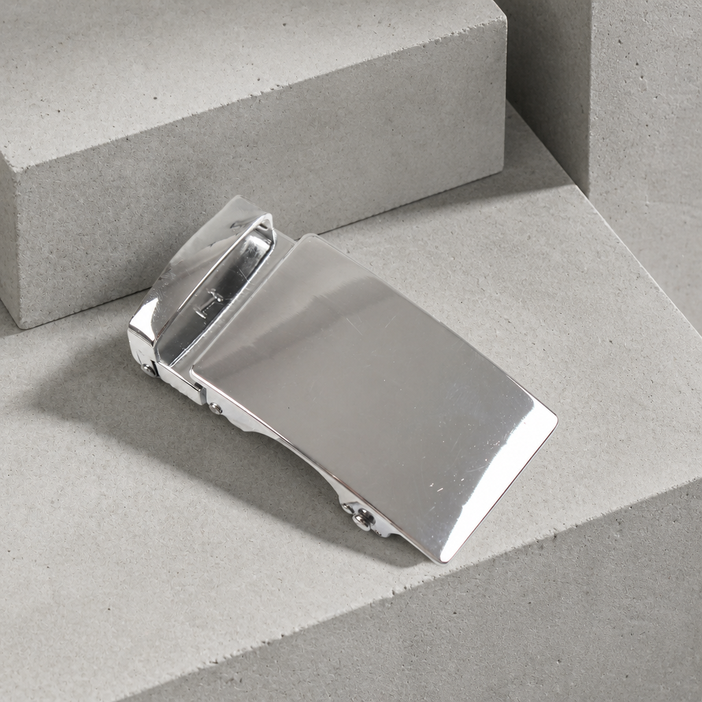 Boucle de ceinture automatique pour homme, finition argent poli, posée sur un bloc de béton