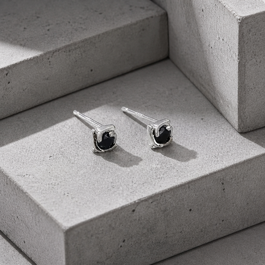Boucles d'oreilles homme diamant noir en argent 925, vue trois quarts sur béton