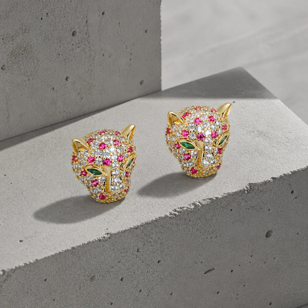 Boucles d'oreilles tête de léopard homme finition or, pavé de zircon blanc et fuchsia, yeux verts, sur béton