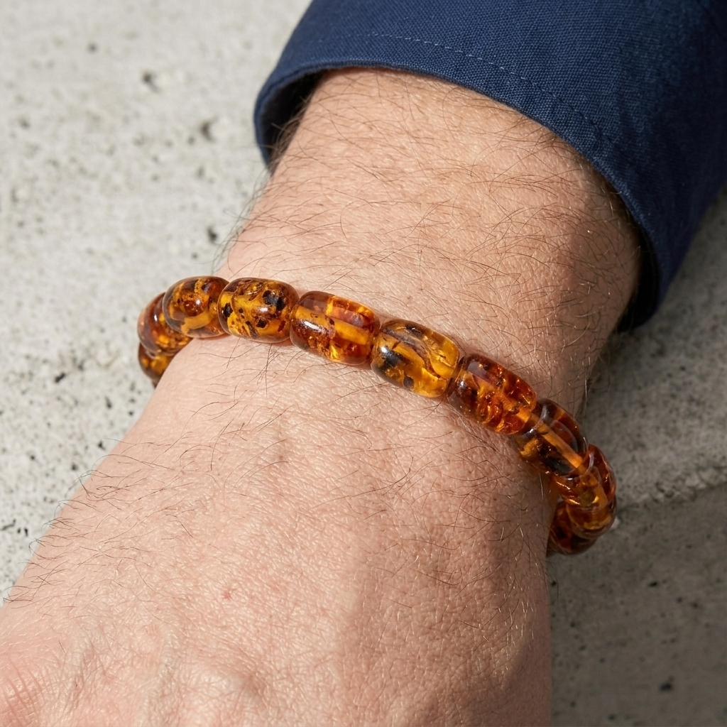 Bracelet ambre homme sur le dessus du poignet, main posée sur du béton