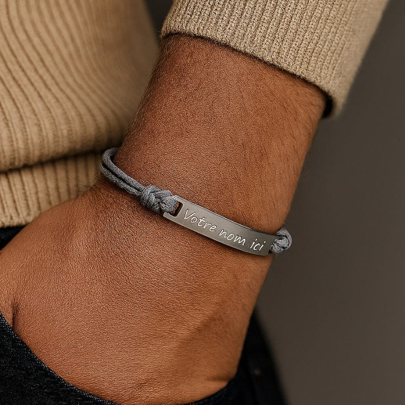 Cordon bracelet homme gris porté au poignet, barrette argent gravée