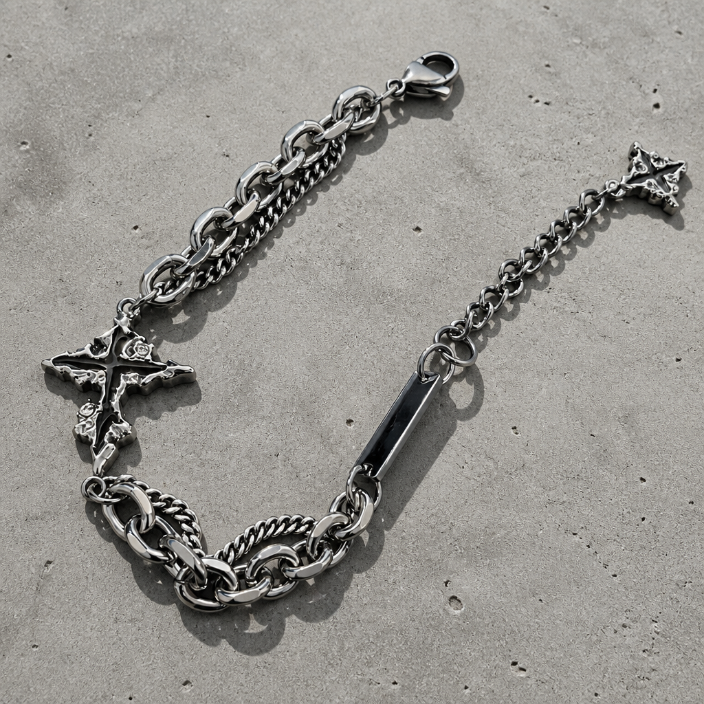 Bracelet croix homme argent déplié sur béton, barrette plate et chaîne de réglage visibles