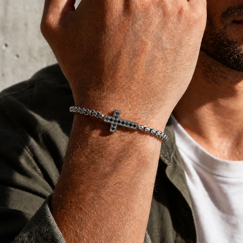 Version argentée portée au poignet, maille fine et croix noire discrète