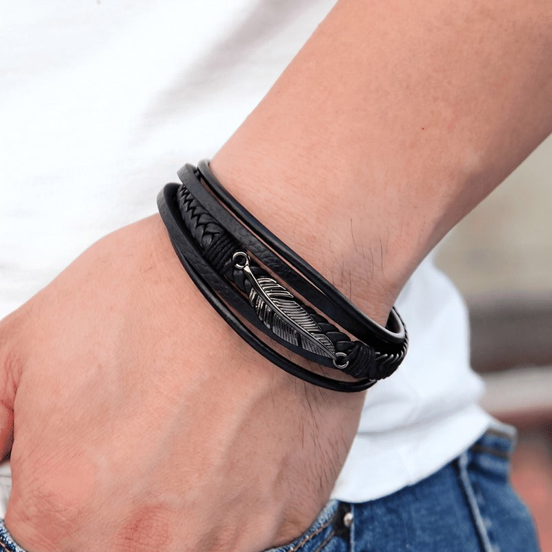 Bracelet cuir noir homme porté au poignet, plume noire fondue dans le cuir