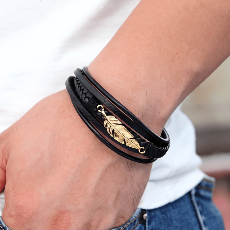 Bracelet cuir noir homme porté au poignet, plume dorée sur cinq brins