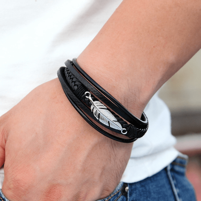 Bracelet cuir et plume acier argent porté au poignet avec un t-shirt blanc