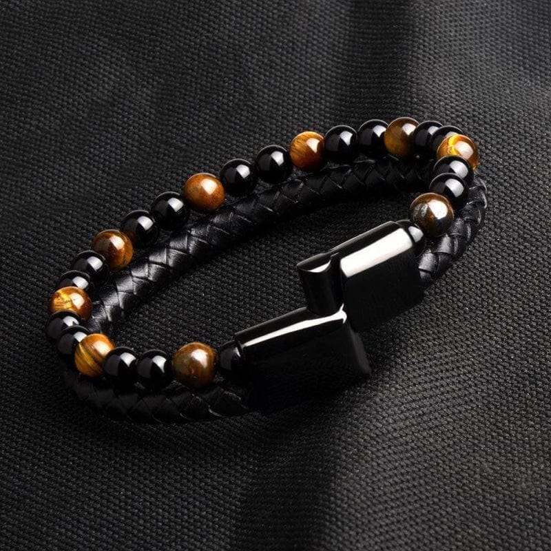 Bracelet homme perles d'œil de tigre et cuir tressé posé sur un tissu sombre