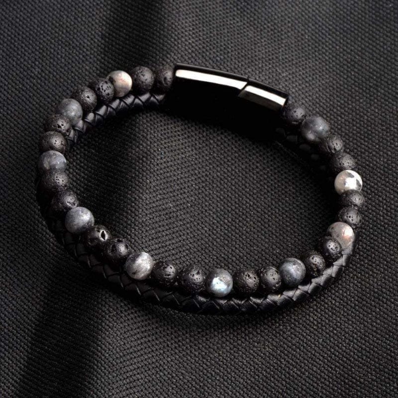 Bracelet homme perles de pierre de lave et cuir tressé posé sur un tissu sombre