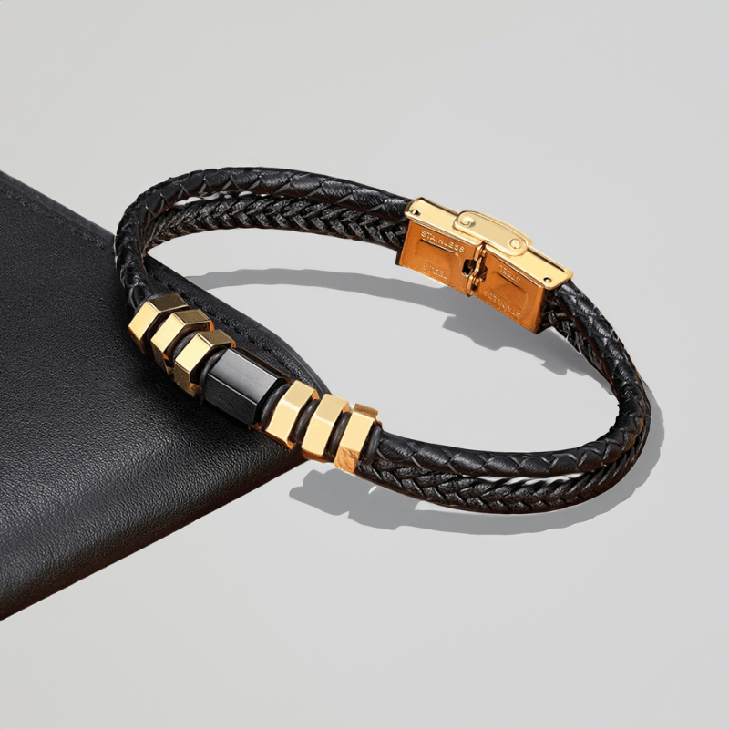 Bracelet homme fin en cuir tressé doré posé sur un cuir sombre