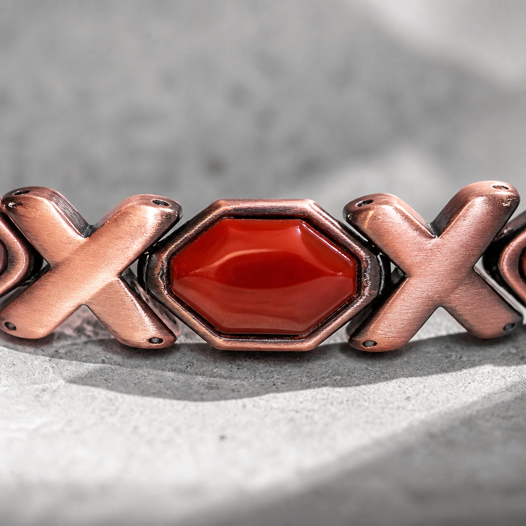 Macro d'un cabochon rouge serti entre deux maillons en X cuivrés brossés
