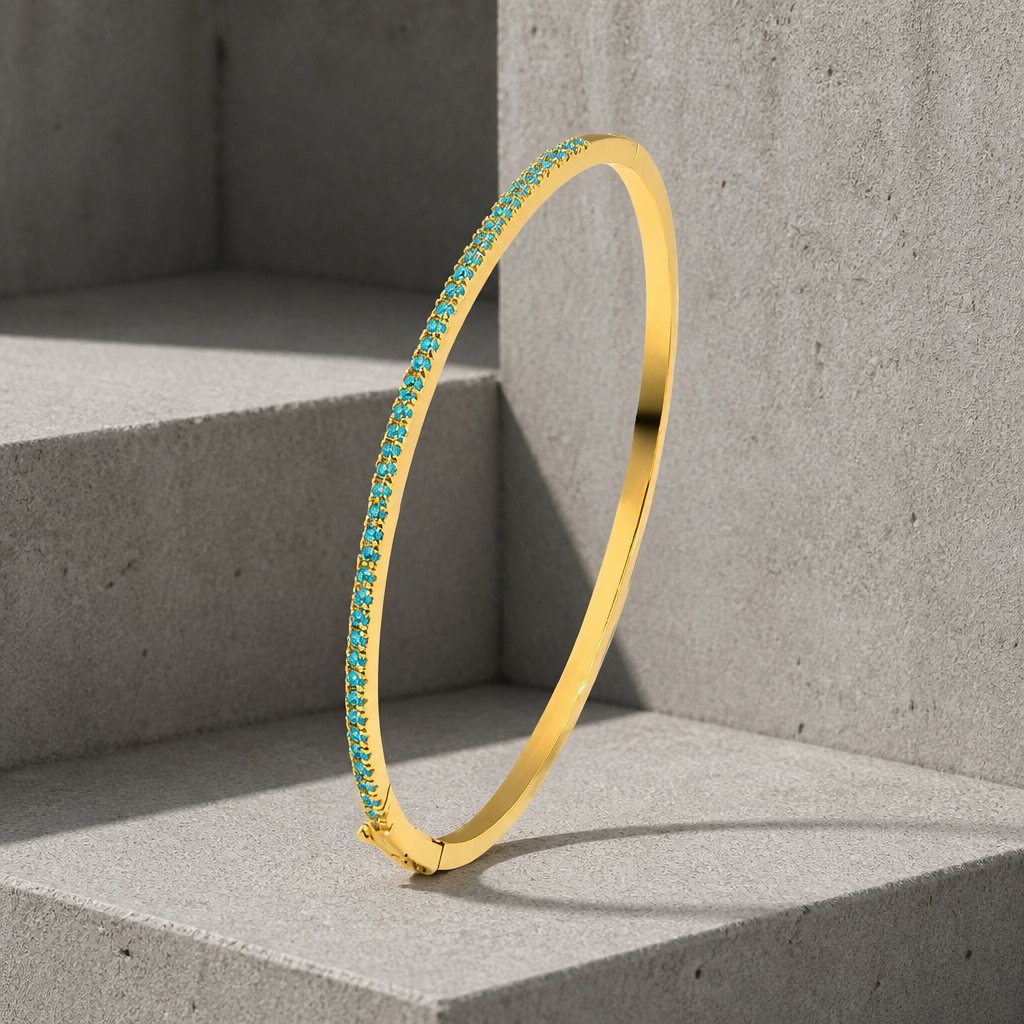 Bracelet homme discret : jonc fin doré à rang de pierres bleues, dressé sur du béton