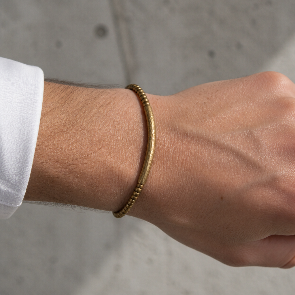 Bracelet en laiton doré porté au poignet d'un homme sous une manchette de chemise