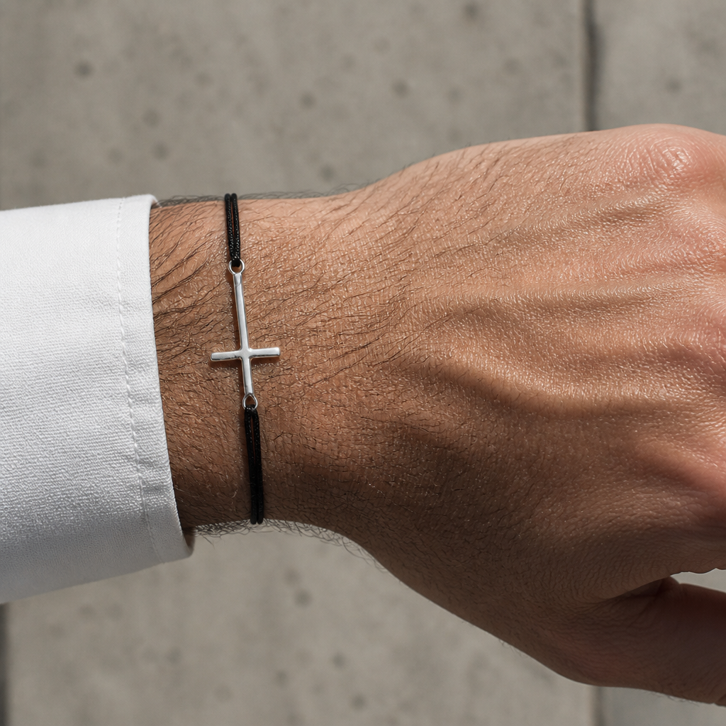 Bracelet à croix argentée porté au poignet sous une manchette de chemise