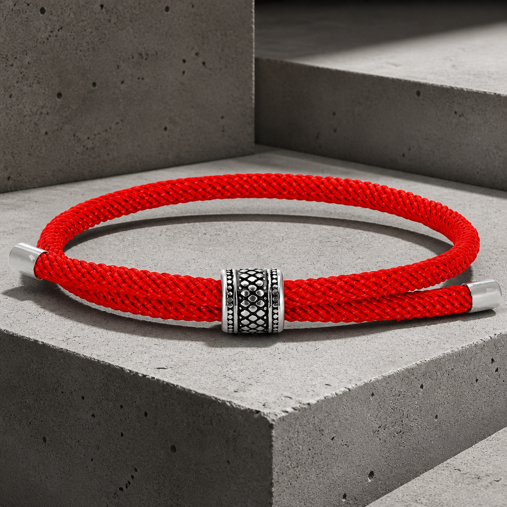 Coloris rouge franc du bracelet, la bague gravée posée au milieu du cordon