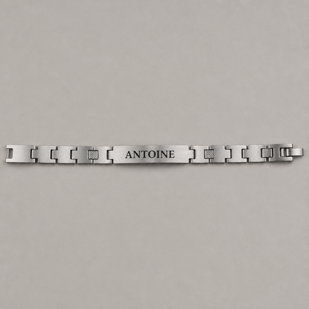 Bracelet homme en acier brossé posé à plat, longue plaque gravée d'un prénom et maillons en H