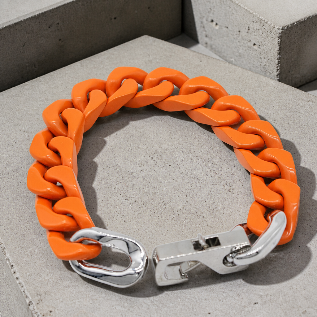 Bracelet homme orange en maille cubaine laquée, packshot sur béton clair
