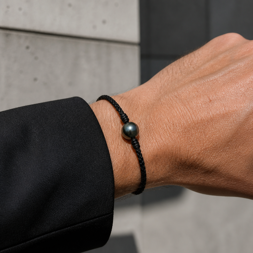 Bracelet une perle de Tahiti porté au poignet d'un homme, cordon noir
