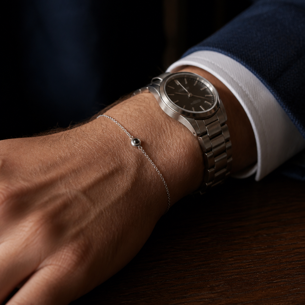 Bracelet chaîne fine photo porté au poignet à côté d'une montre en acier