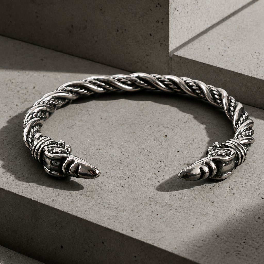 Bracelet jonc homme viking argenté, câble torsadé et deux têtes de corbeau, sur béton clair