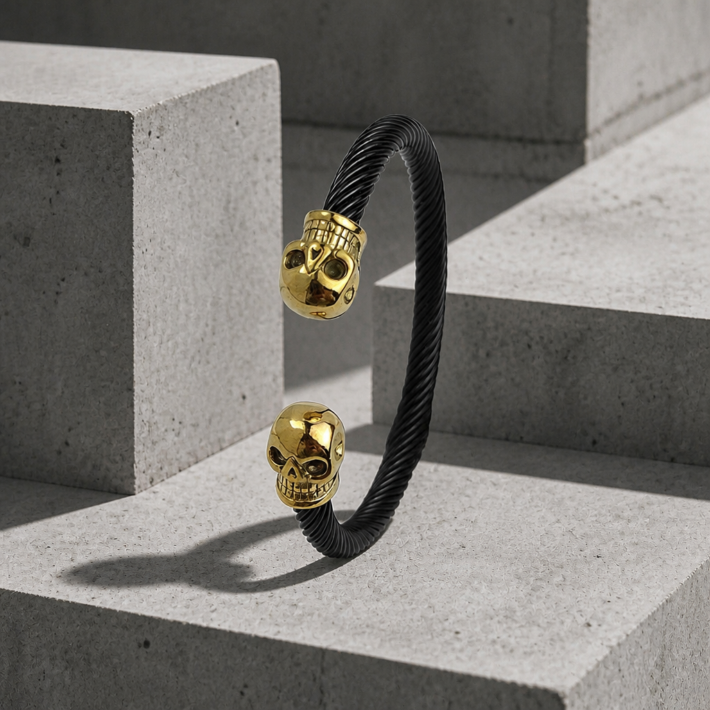 Bracelet motard homme jonc torsadé noir à deux têtes de mort dorées, sur béton