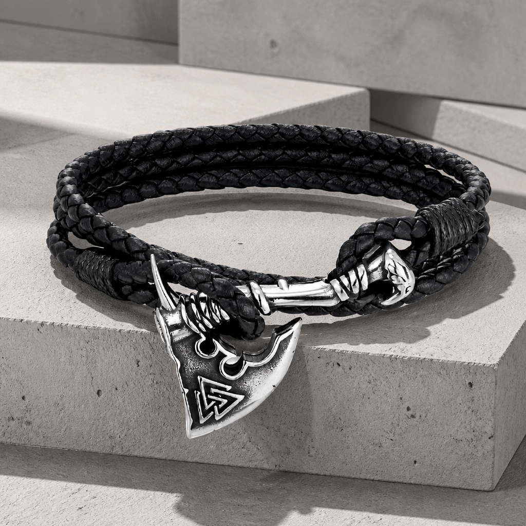 Bracelet nordique homme en cuir tressé noir, hache d'acier gravée, sur du béton
