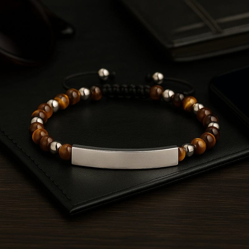 Bracelet homme œil de tigre et barrette acier posé sur un carnet