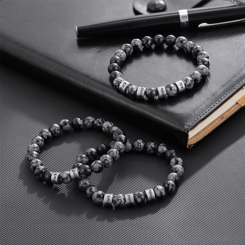 Trois bracelets homme en perles de pierre naturelle posés sur un carnet