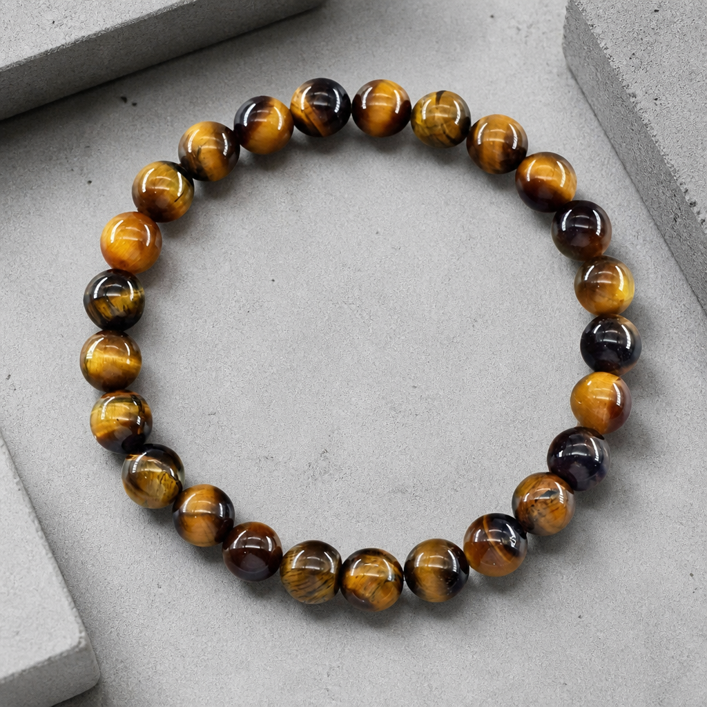 Bracelet protection homme en perles d'œil de tigre posé sur du béton, vue de dessus