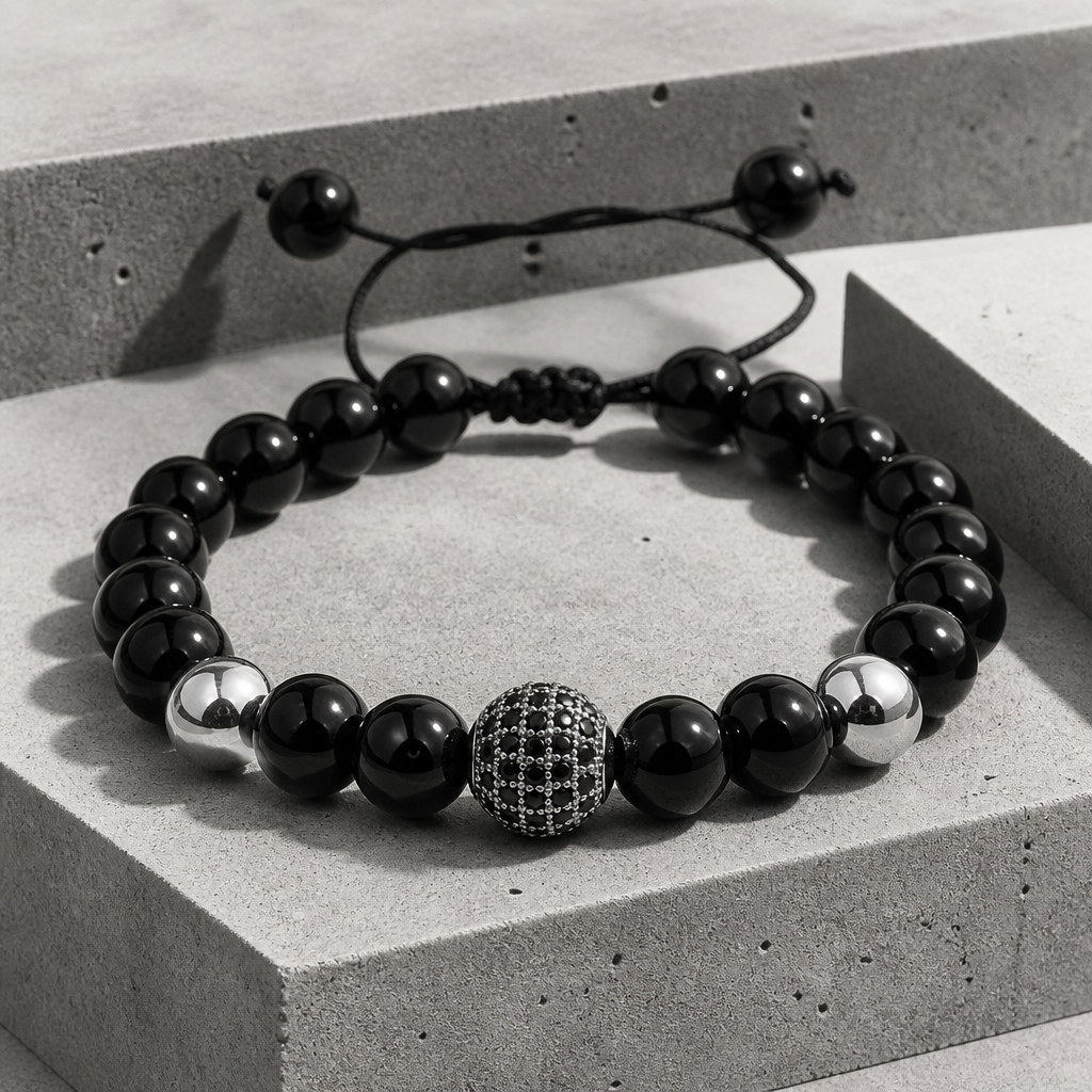 Bracelet shamballa homme, rang de perles noires et bille pavée argentée sur béton
