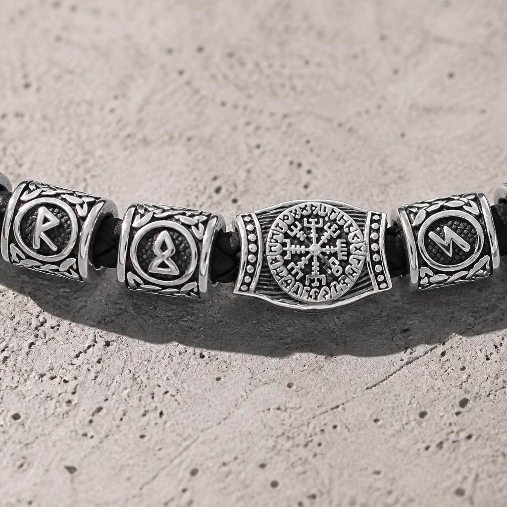Gros plan sur les runes gravées en creux et le compas à huit branches du bracelet