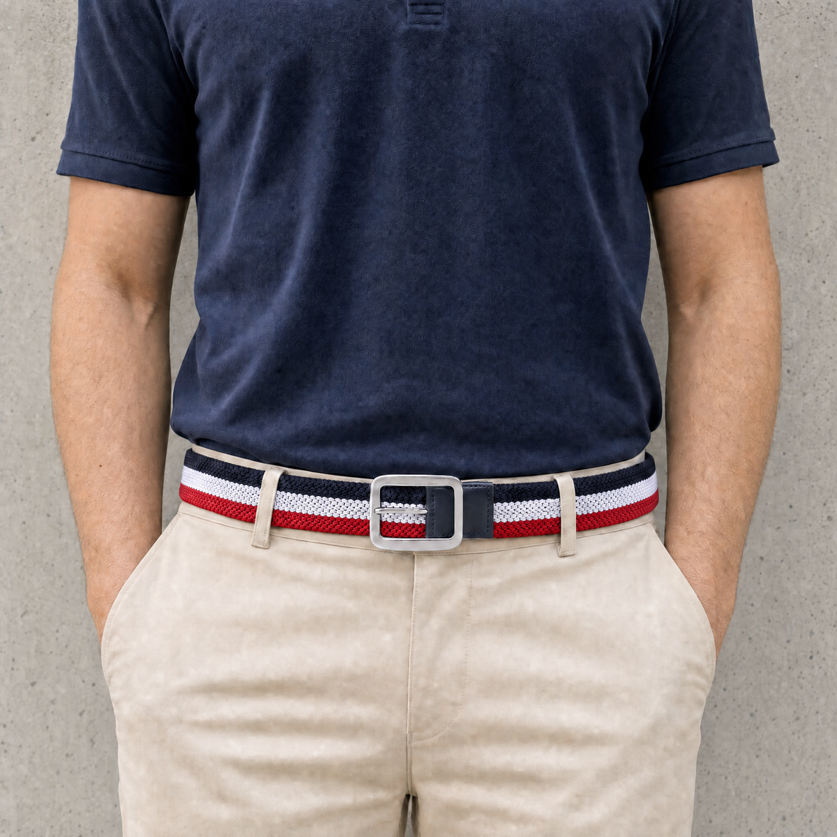 Homme portant la ceinture golf homme tressée rayée bleu marine, blanc et rouge avec un polo marine et un chino beige