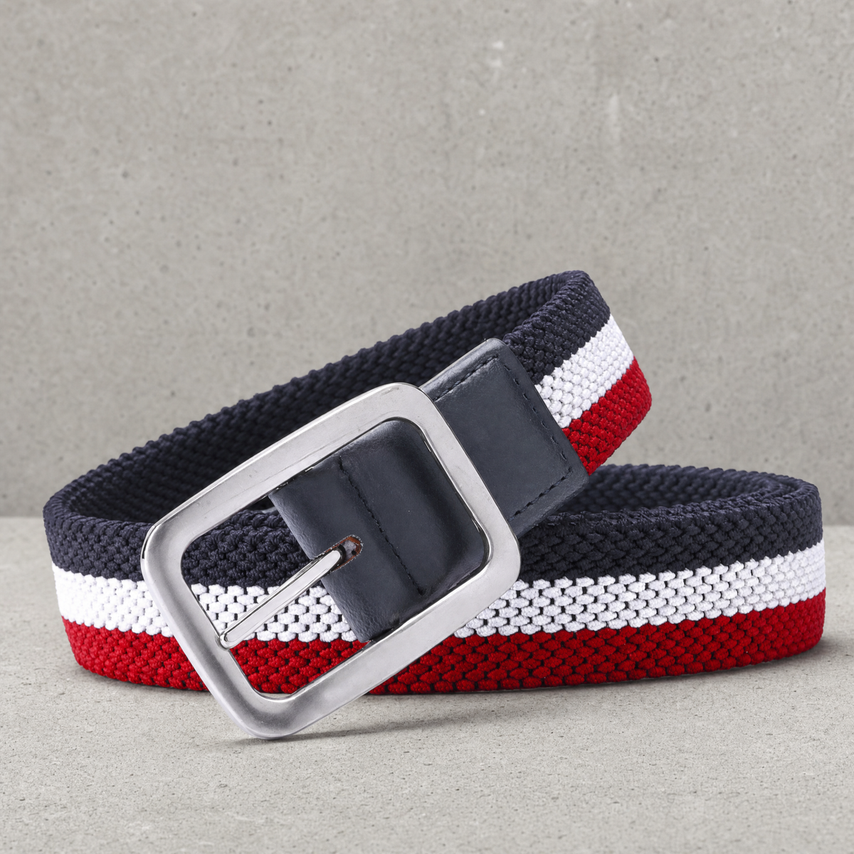 Ceinture golf homme tressée élastique rayée bleu marine, blanc et rouge, boucle argent brossé, posée enroulée