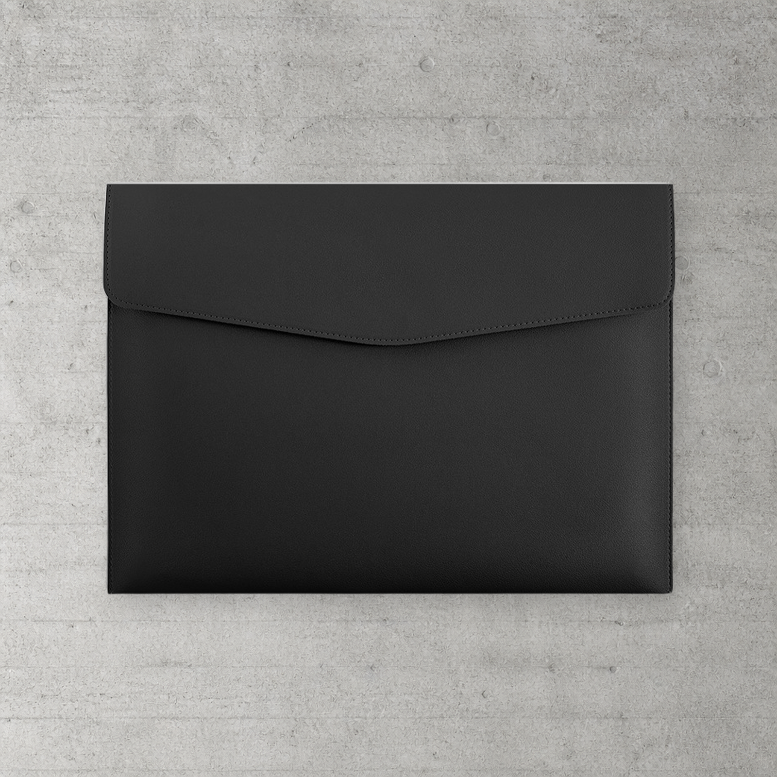 Chemise porte-document A4 en simili cuir noir à fermoir magnétique, posée sur béton clair