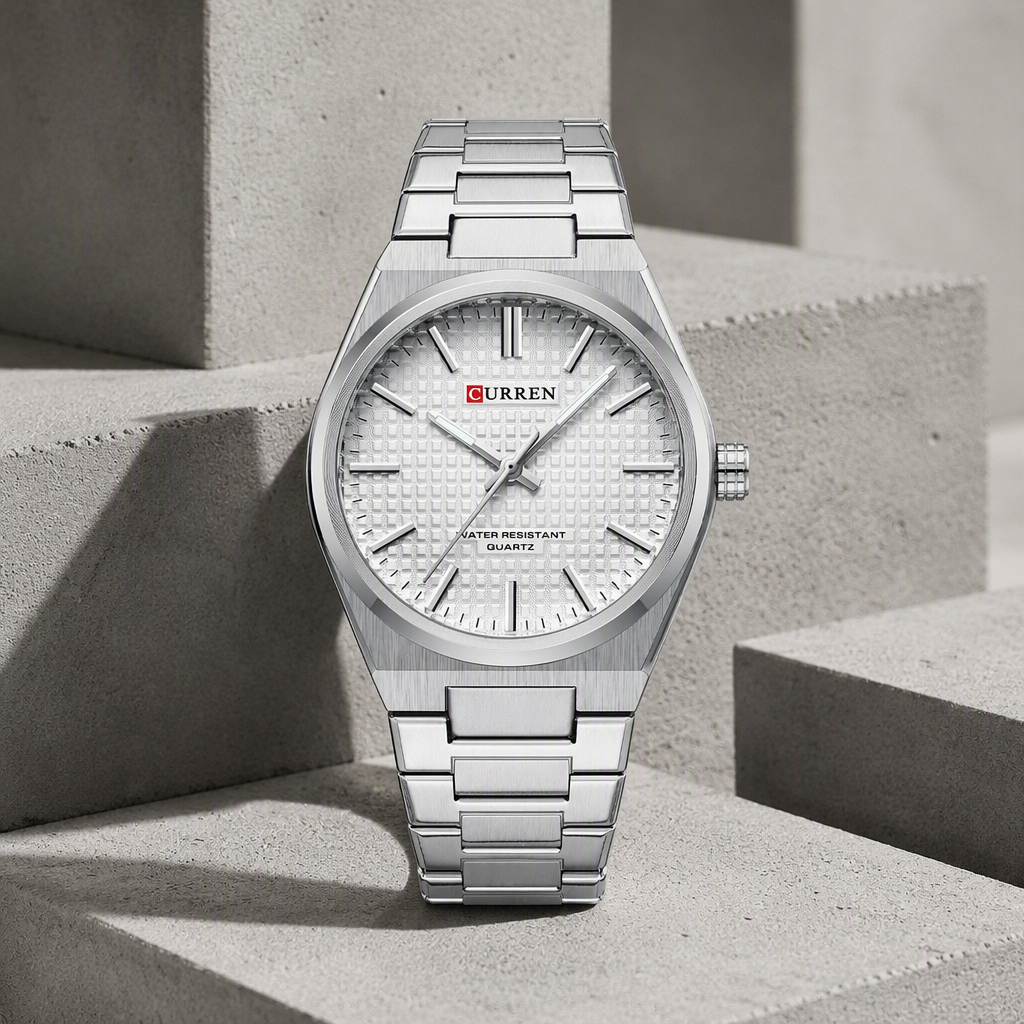 Montre homme ronde en acier au cadran blanc texturé, posée sur du béton