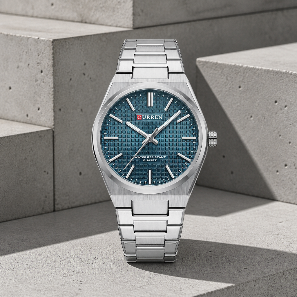 Montre homme ronde en acier au cadran bleu pétrole texturé, posée sur du béton