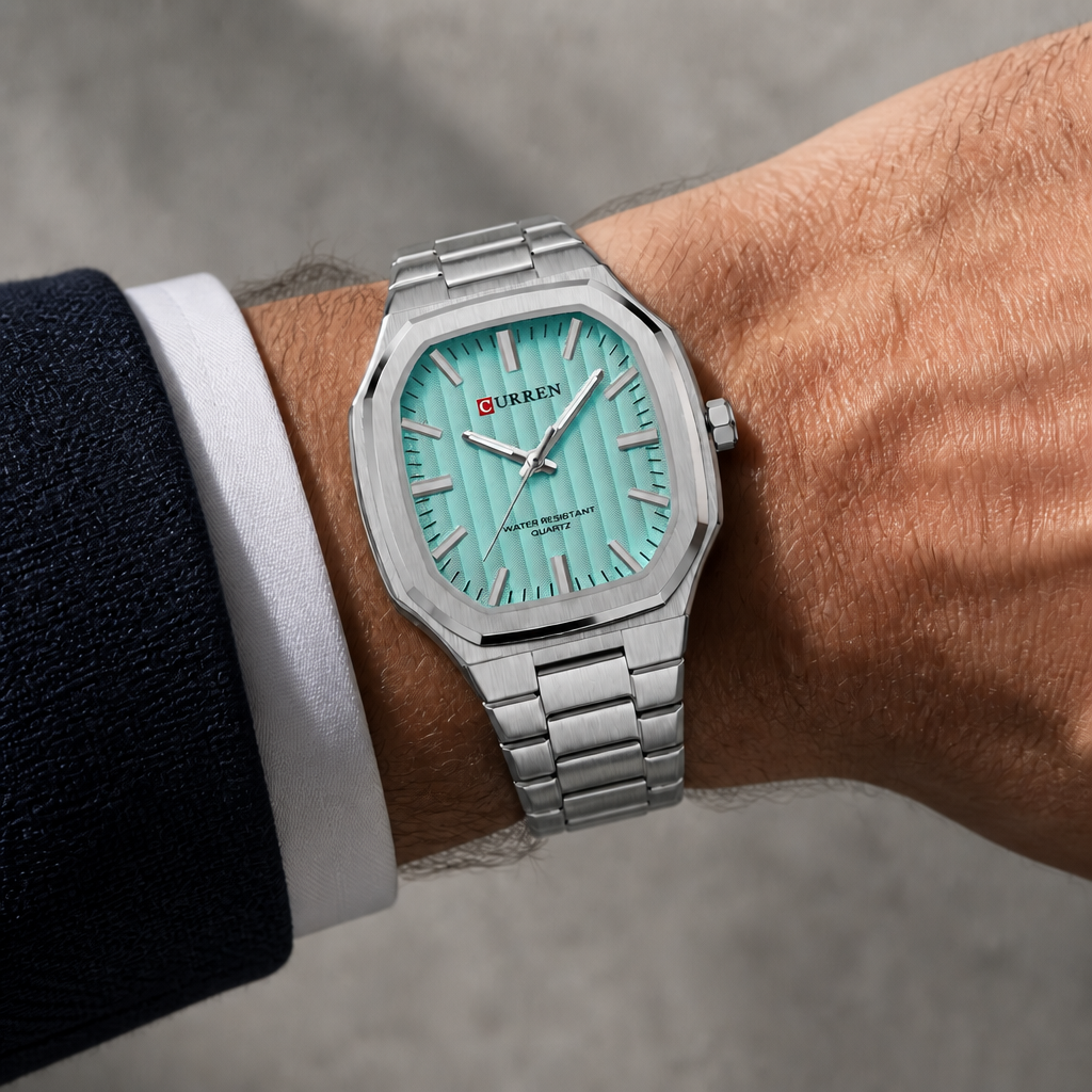 Montre carrée à cadran vert d'eau portée au poignet sous une manchette de chemise