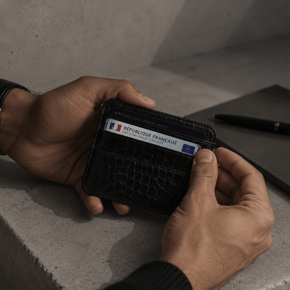 Homme tenant un porte-cartes façon crocodile noir avec ses cartes