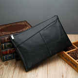 Pochette en cuir noir pour homme posée sur des livres